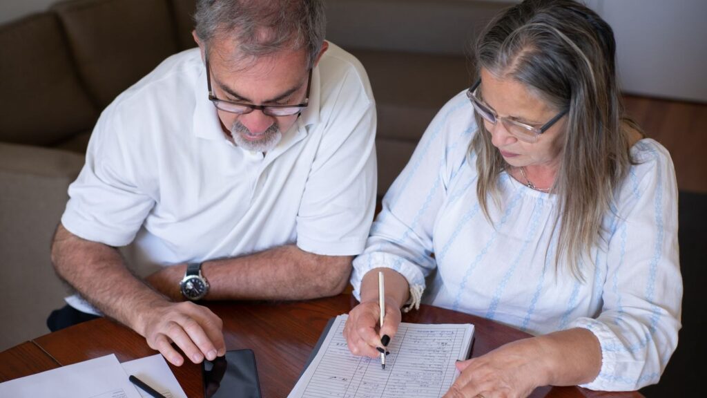 Tax rumours are driving pension withdrawals that could prove costly later: an older couple going through pension and retirement paperwork together at home